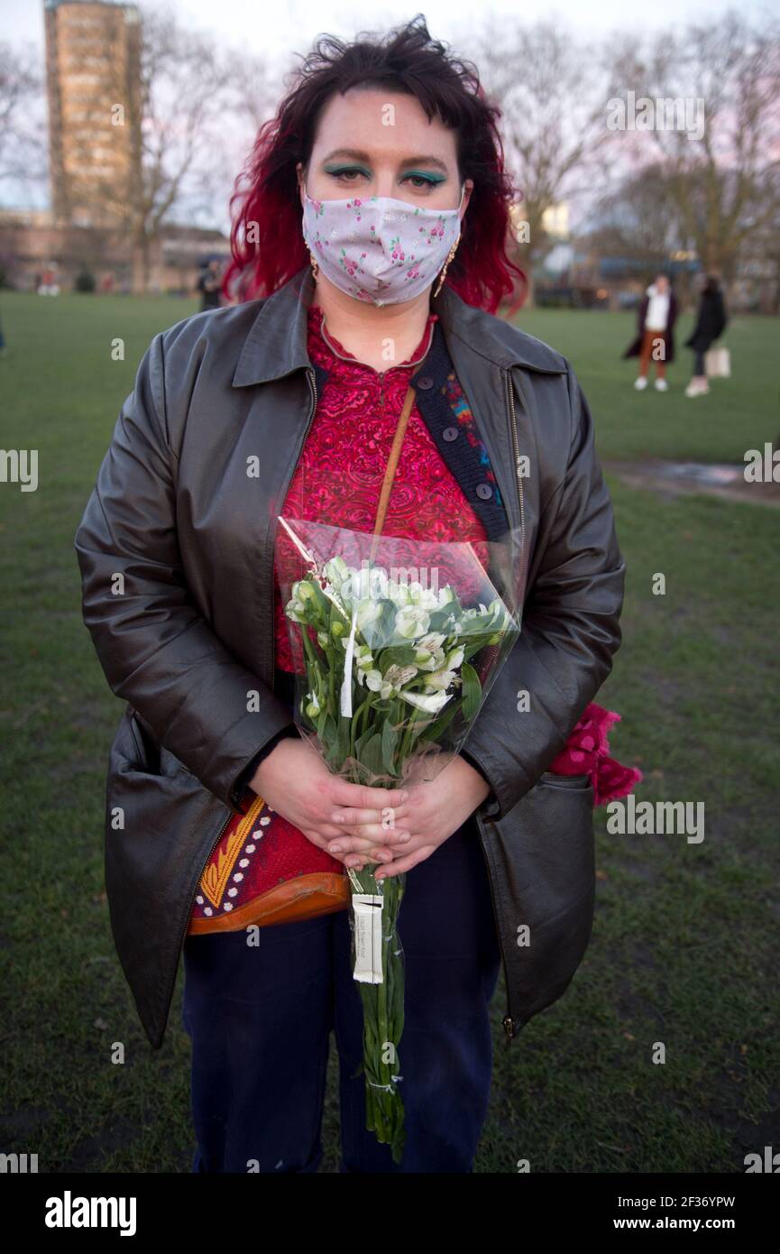London Fields, Hackney 13/03/2021 Vigil pour Sarah Everard, un policier en service, a été accusé de son meurtre. Une jeune femme tient un tas de fleurs Banque D'Images