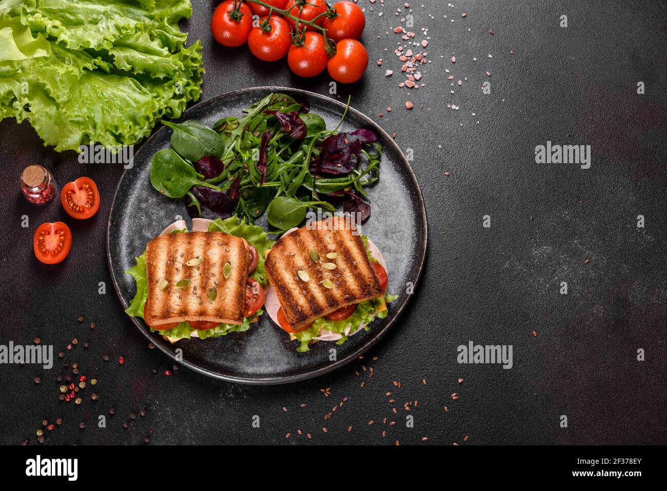 Délicieux sandwich avec toasts croquants, jambon, laitue et tomates. Petit déjeuner nourrissant rapide Banque D'Images