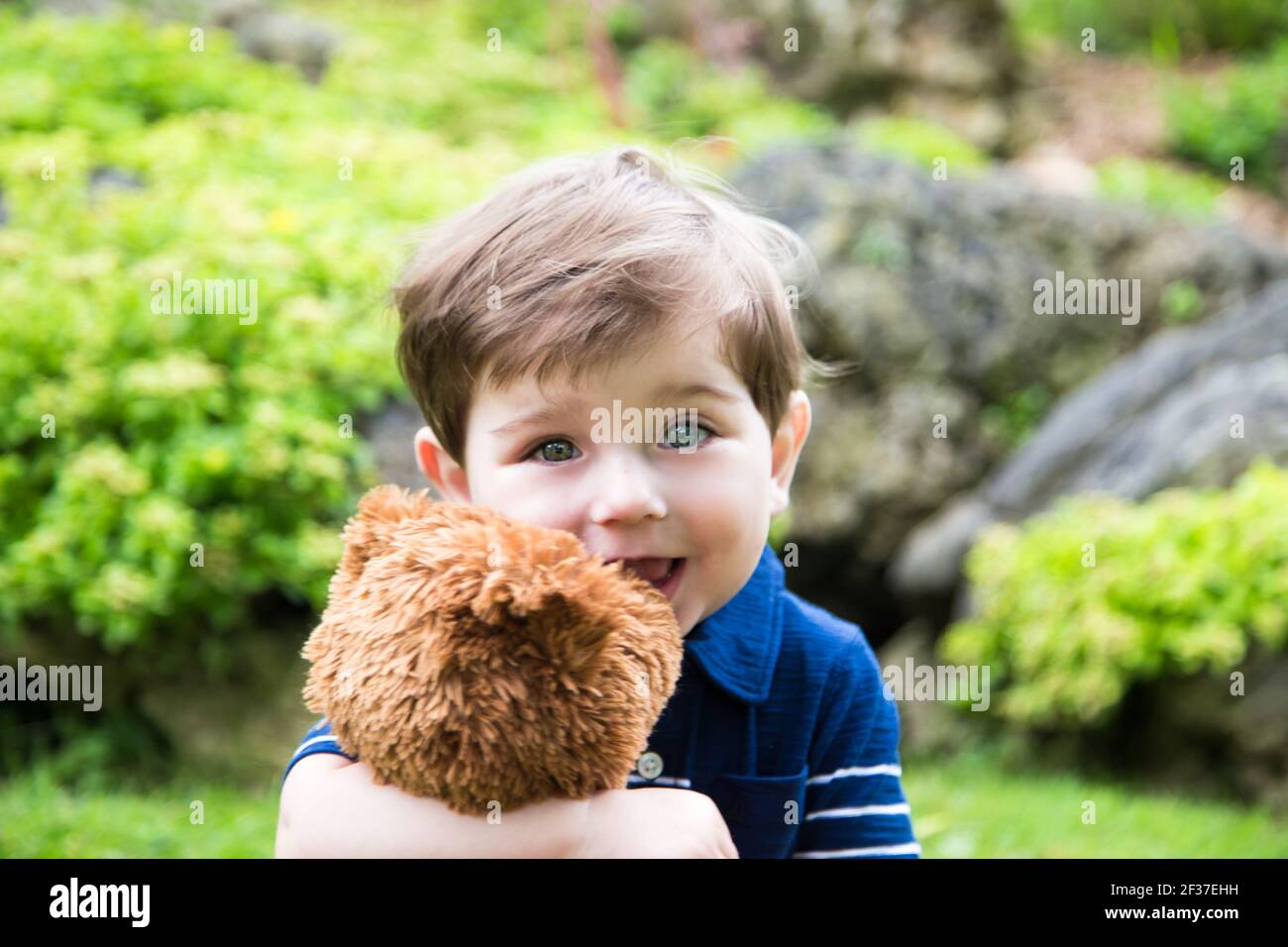 petit garçon jouant avec un ours en peluche dans le jardin Banque D'Images