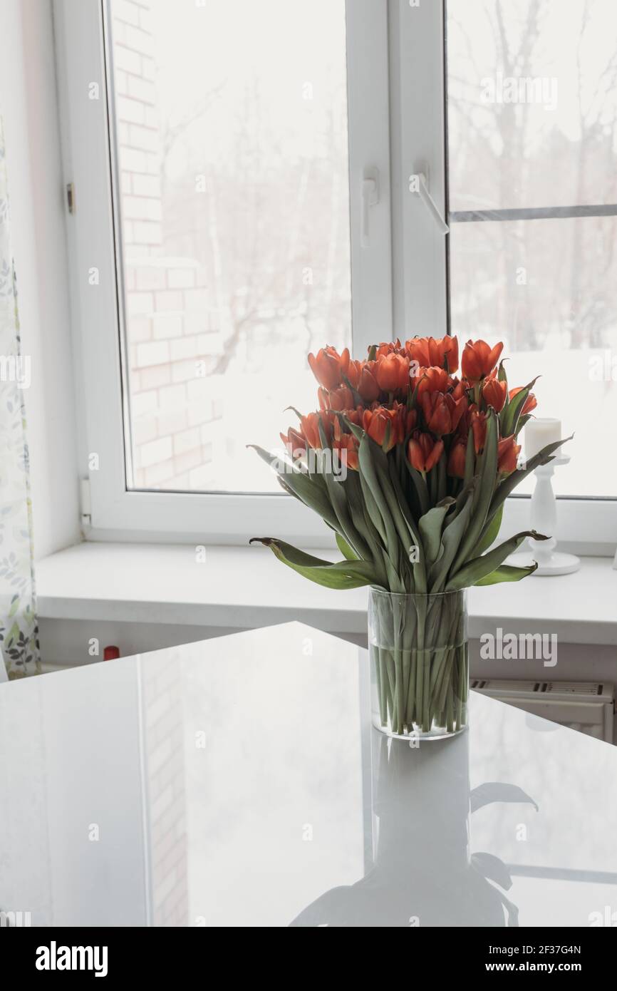 un bouquet de tulipes dans un vase transparent sur un tableau blanc contre Banque D'Images