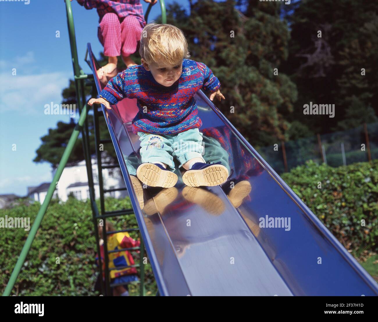 Jeune garçon sur la diapositive en aire de jeux, Berkshire, Angleterre, Royaume-Uni Banque D'Images