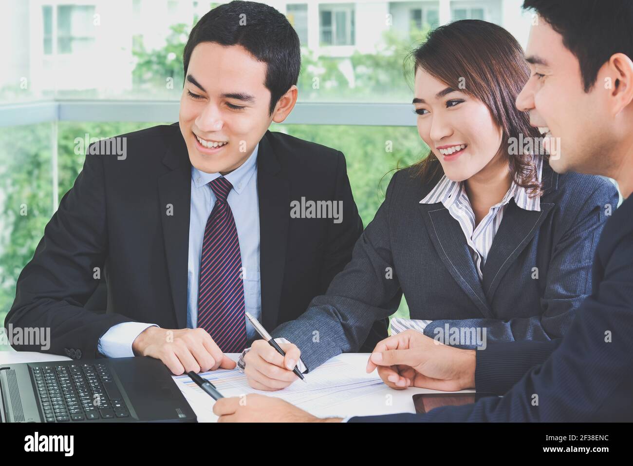 Des hommes d'affaires asiatiques discutant et souriant lors d'une réunion, ton doux Banque D'Images