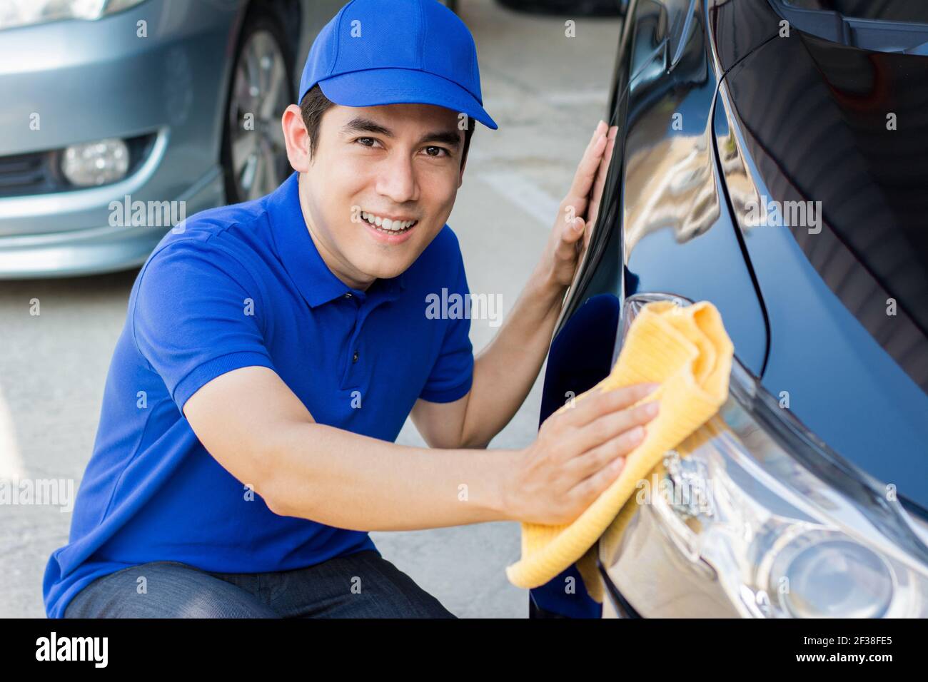 Jeune homme polissage (nettoyage) voiture avec tissu en microfibre - habillage de voiture, valeting et auto concepts de service Banque D'Images