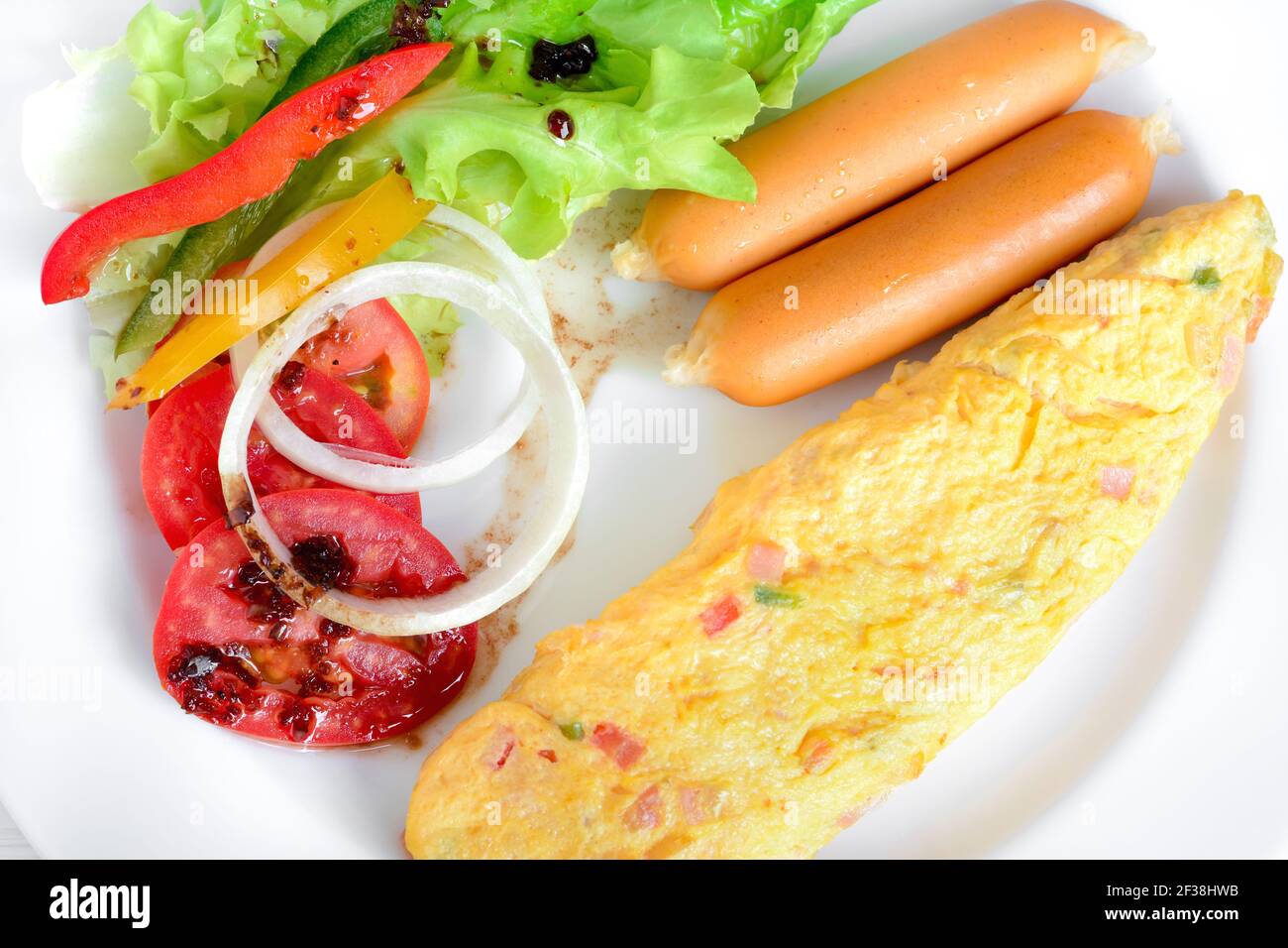 Petit-déjeuner comprenant omelette, saucisse et salade colorée avec vinaigrette italienne Banque D'Images