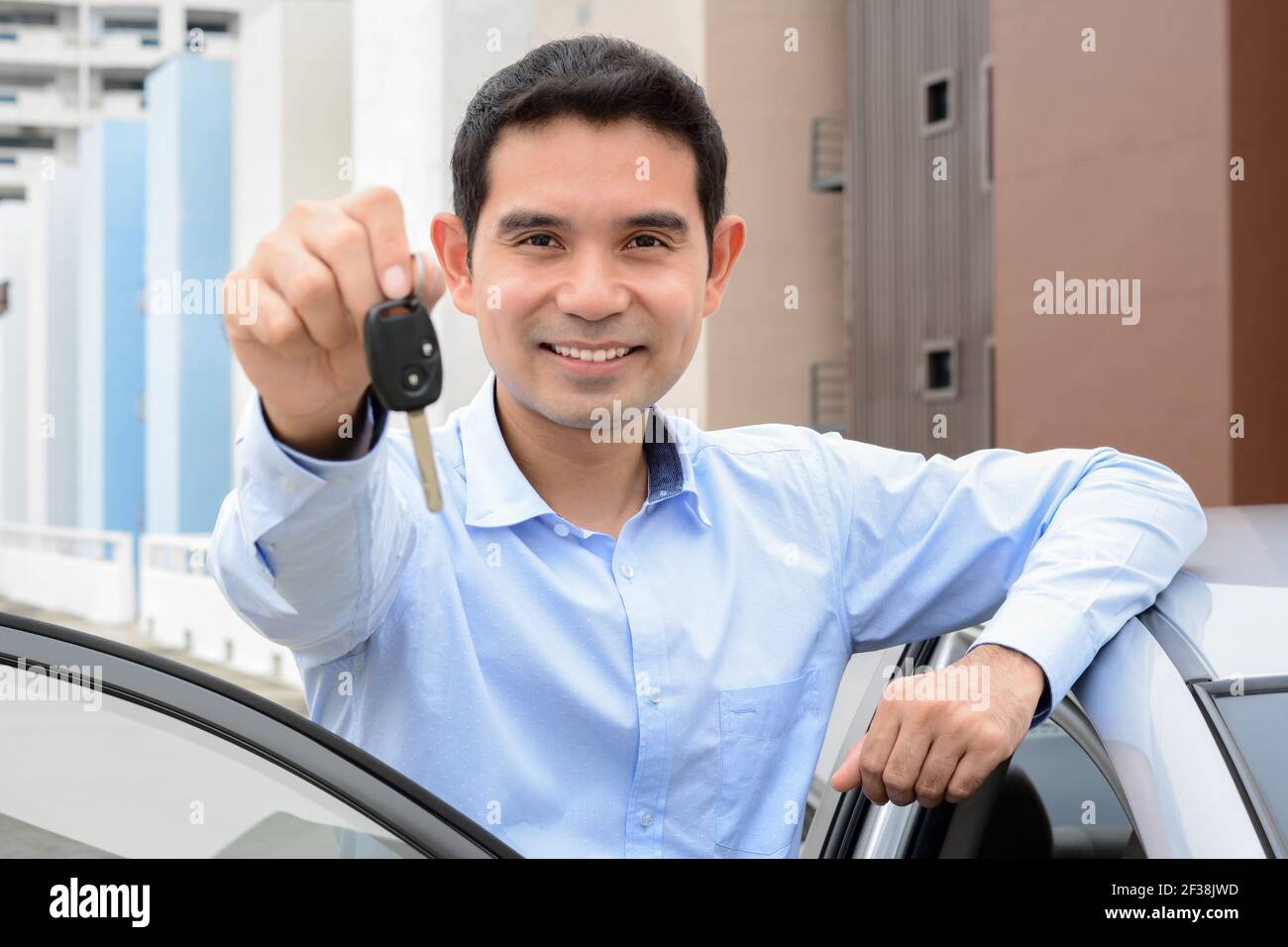 Homme asiatique souriant montrant la clé de la voiture (orienté visage) Banque D'Images