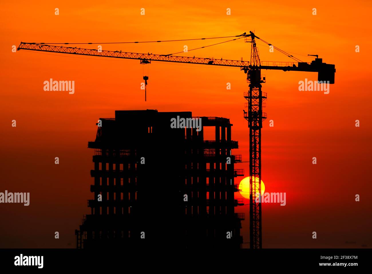 Silhouette de la tour de grue et du bâtiment en construction au crépuscule arrière-plan du coucher du soleil Banque D'Images