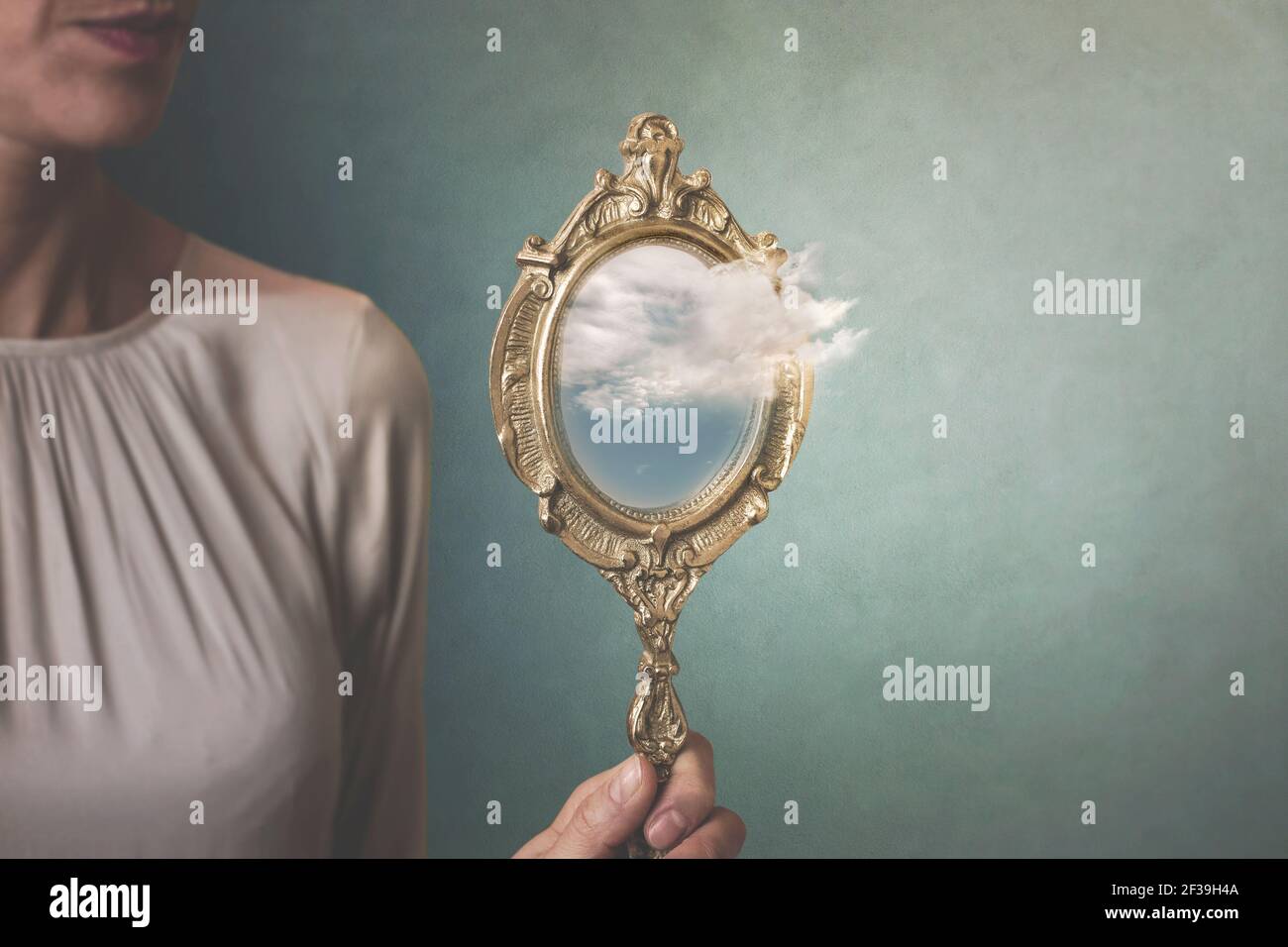 situation surréaliste d'un cloud sortant d'un miroir tenue par une femme Banque D'Images