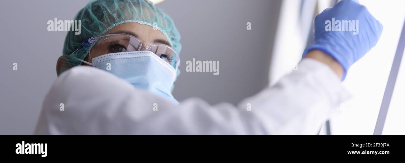 Médecin en lunettes et masque médical et gants tient une image radiologique. Banque D'Images
