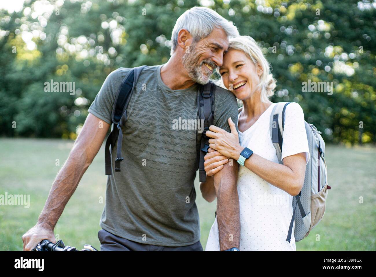 Couple mûr souriant debout dans la forêt Banque D'Images