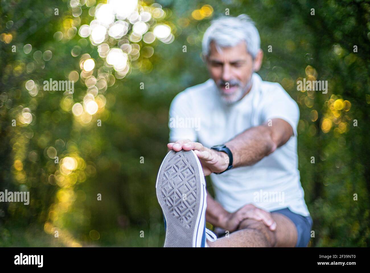 Homme mature qui étire sa jambe en forêt Banque D'Images
