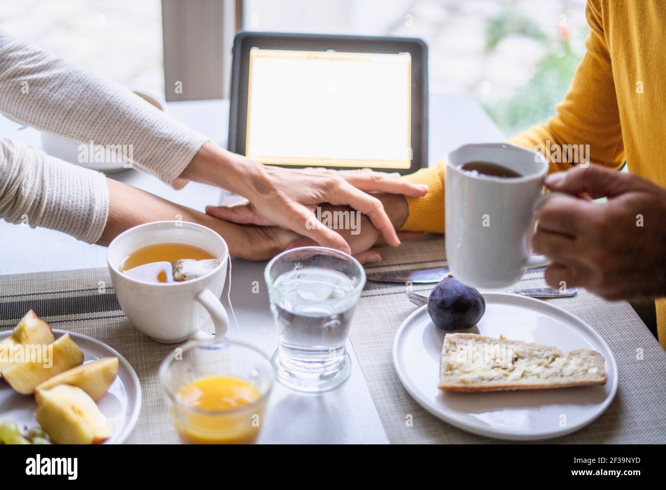 Couple d'âge mûr tenant les mains tout en prenant le petit déjeuner à table Banque D'Images