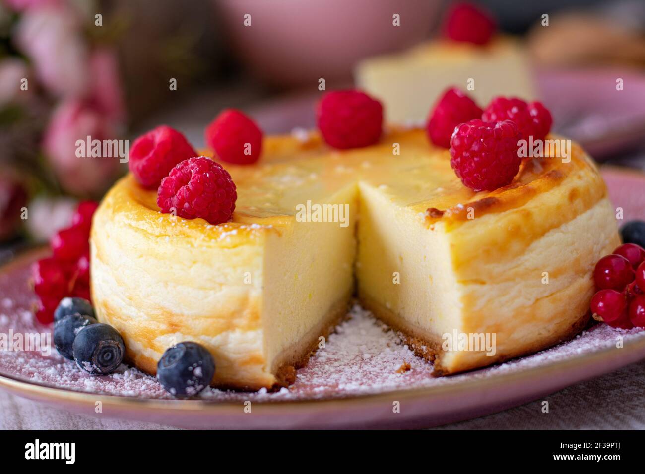 Gros plan d'un gâteau au fromage accompagné de framboises une assiette rose pâle Banque D'Images