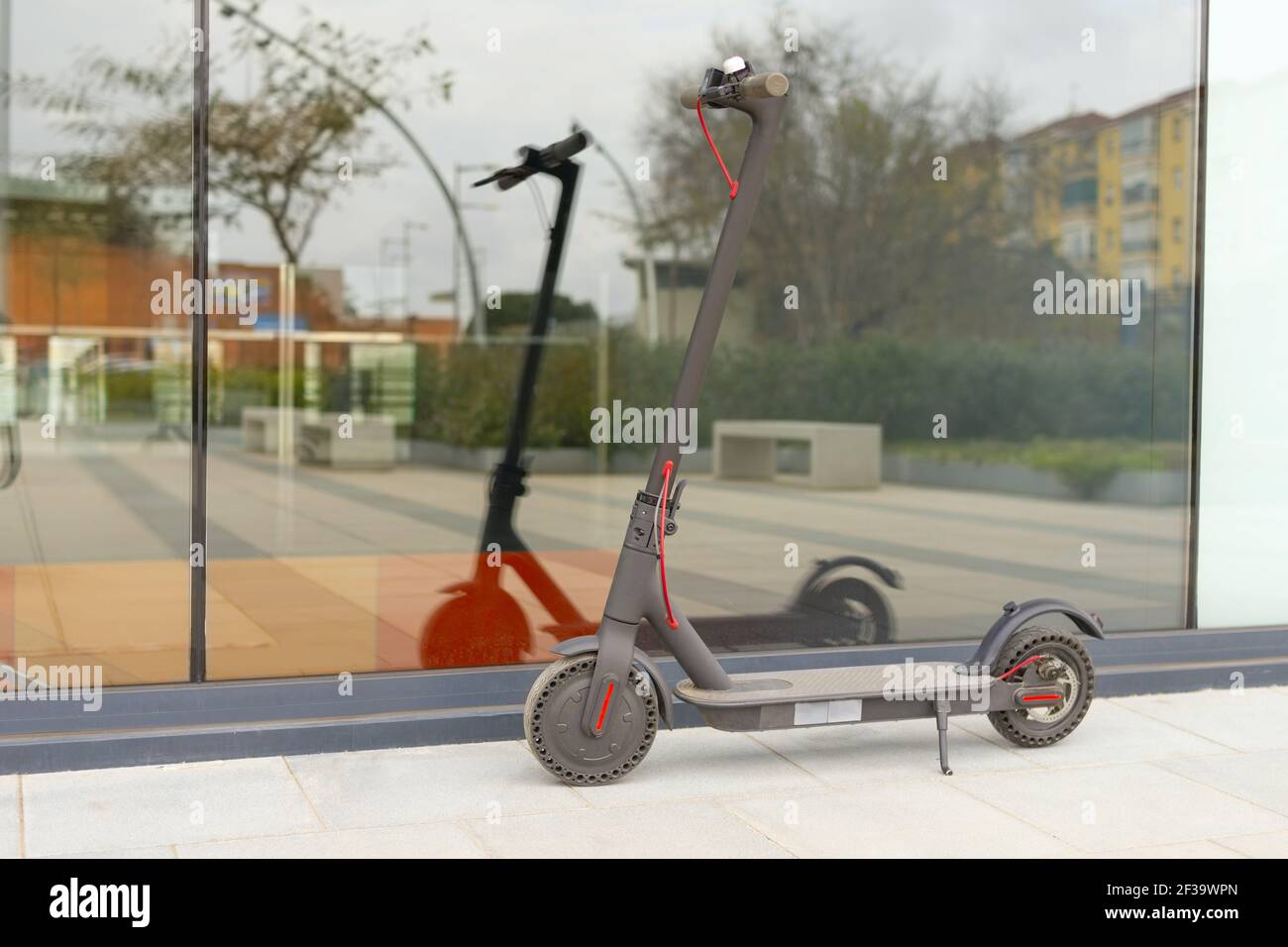 image d'un scooter électrique gris les reflétant sur un grand verre dans un carré Banque D'Images