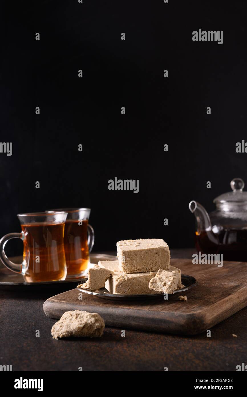 Halva orientale et thé chaud sur fond marron foncé. Orientation verticale. Banque D'Images