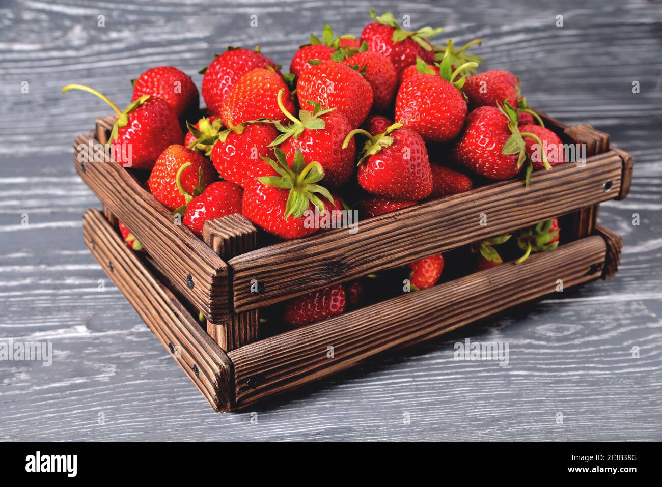 Fraises dans une boîte en bois sur un fond gris en bois naturel, flou comme une technique artistique de l'auteur espace de copie de gros plan Banque D'Images