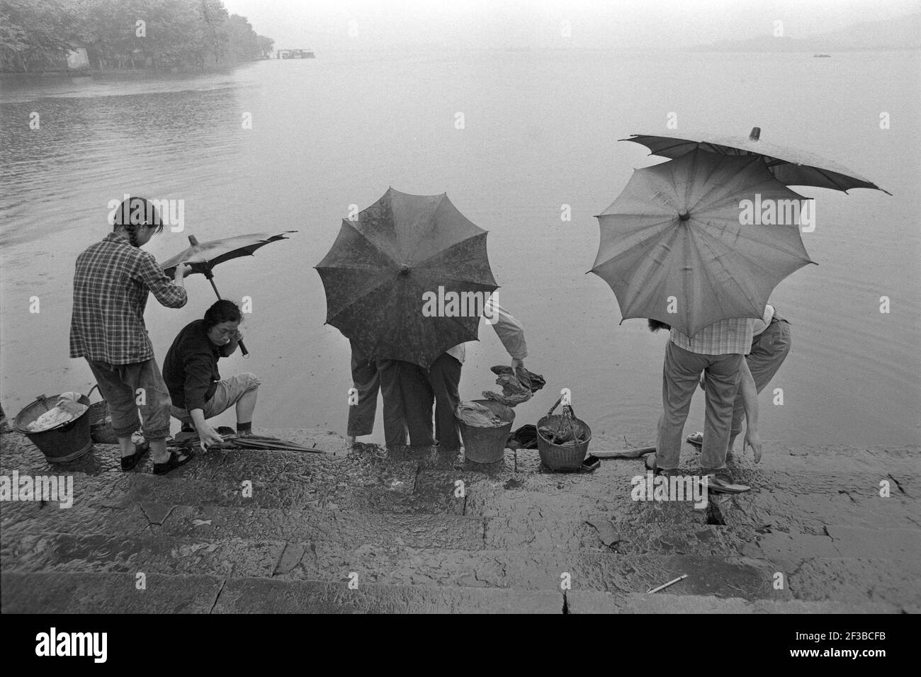 Les femmes de bain chinoises lavent leur linge dans un lac près de Hangchou, elles portent des parapluies, 02.06.1973 | usage dans le monde entier Banque D'Images