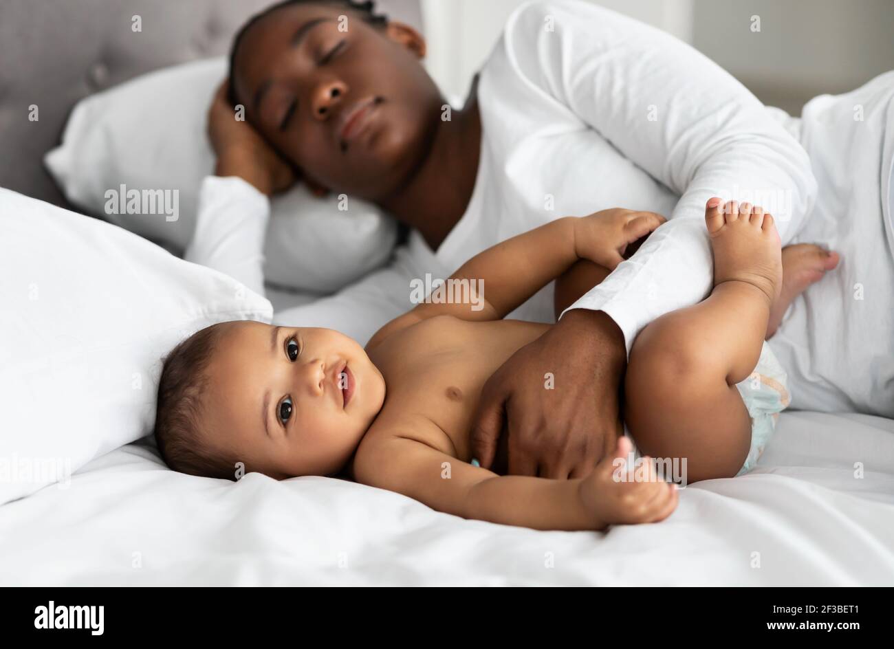 Mignon petit Afro-américain bébé dormant dans le lit avec maman Banque D'Images