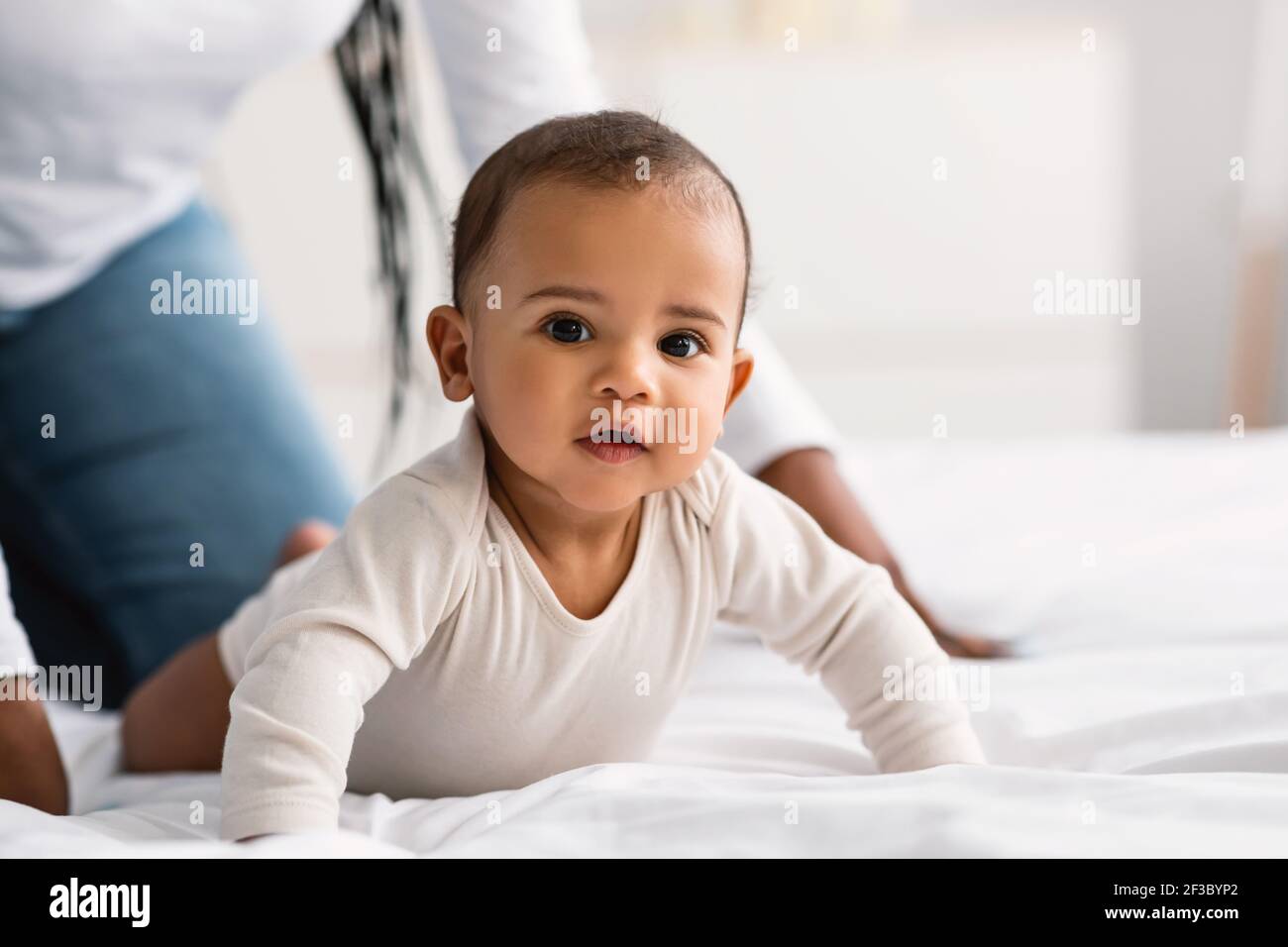 Mignon petit Afro-américain bébé rampant dans le lit Banque D'Images