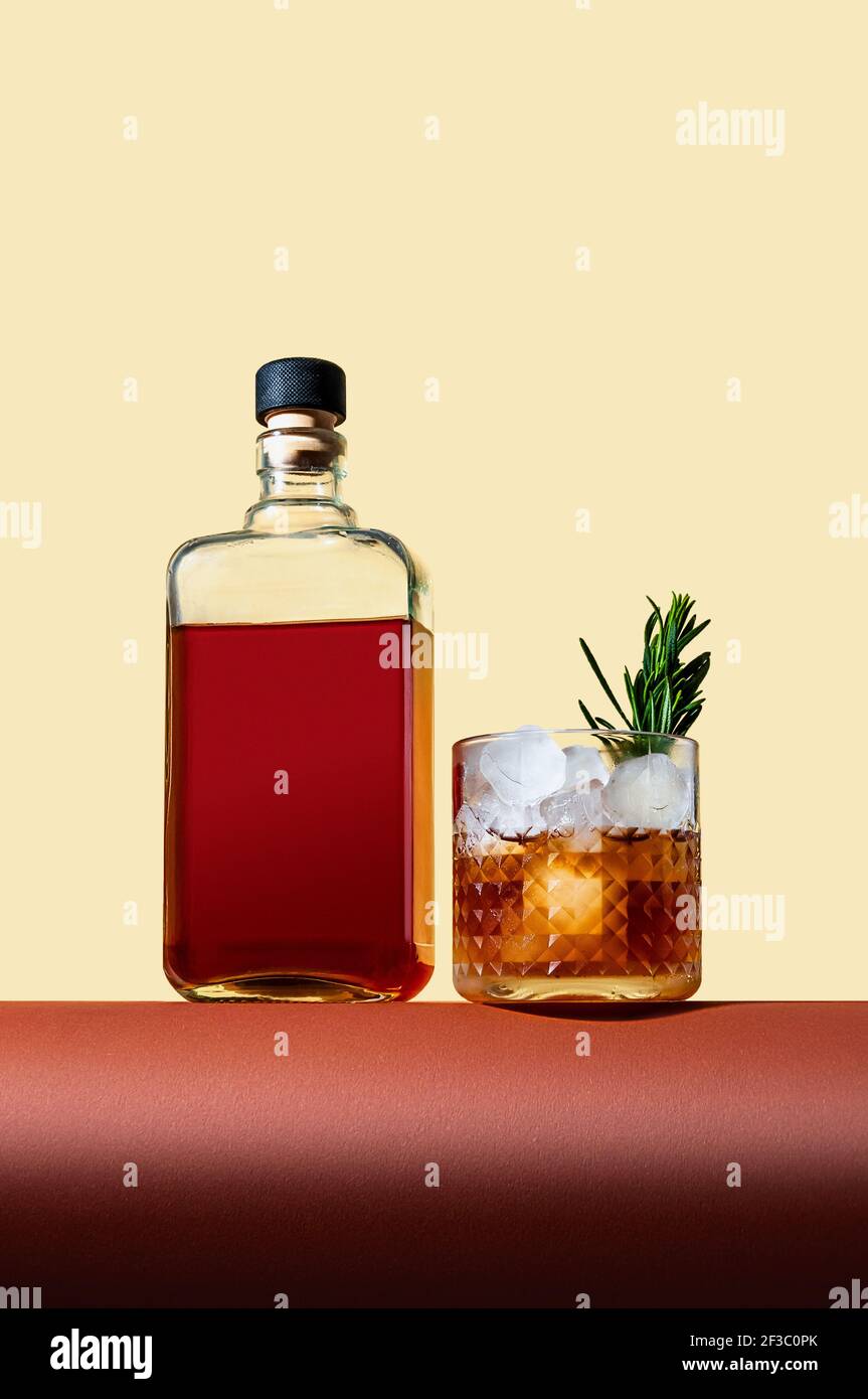 Bouteille et verre avec Whiskey et glace sur table brune sur fond clair. Style moderne. Concept créatif. Banque D'Images