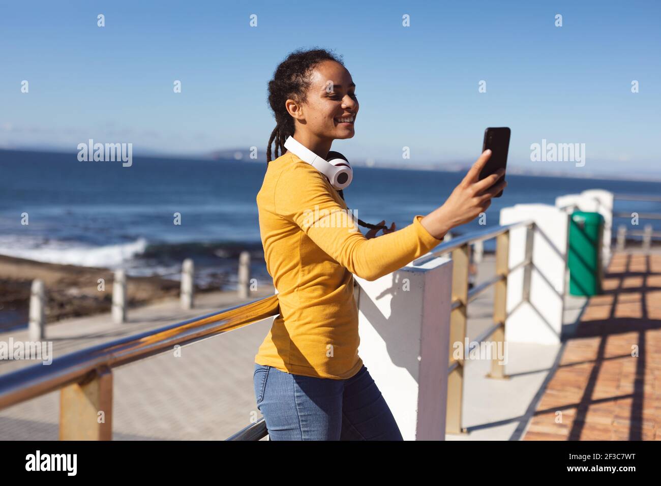 Femme afro-américaine souriante prenant le selfie avec un smartphone près du mer Banque D'Images