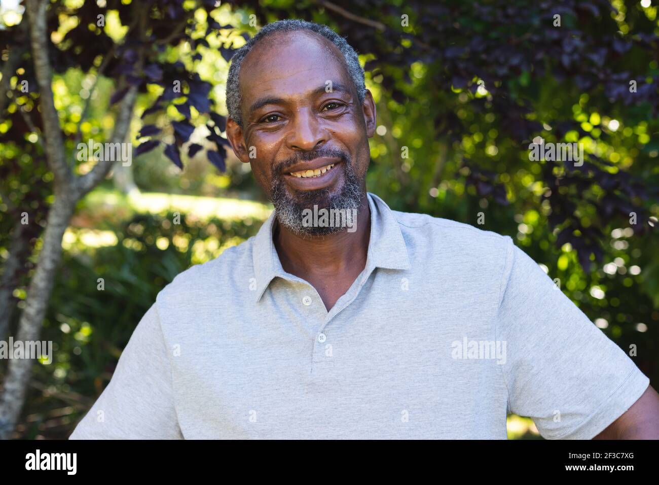 Portrait de l'homme senior de course mixte dans le jardin regardant appareil photo et sourire Banque D'Images