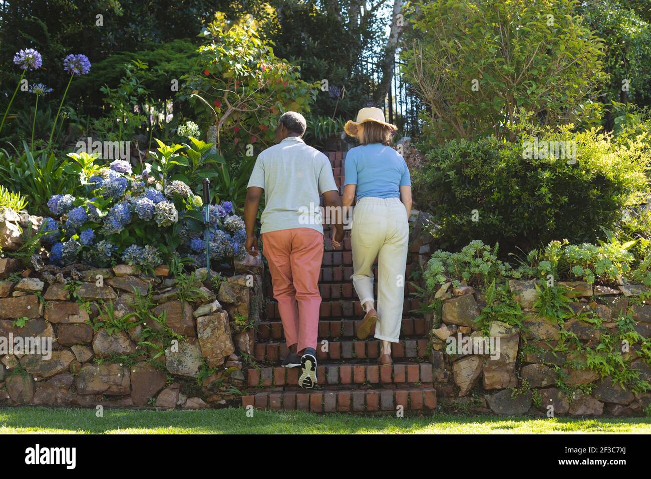 Divers couples âgés marchant dans le jardin tenant les mains Banque D'Images