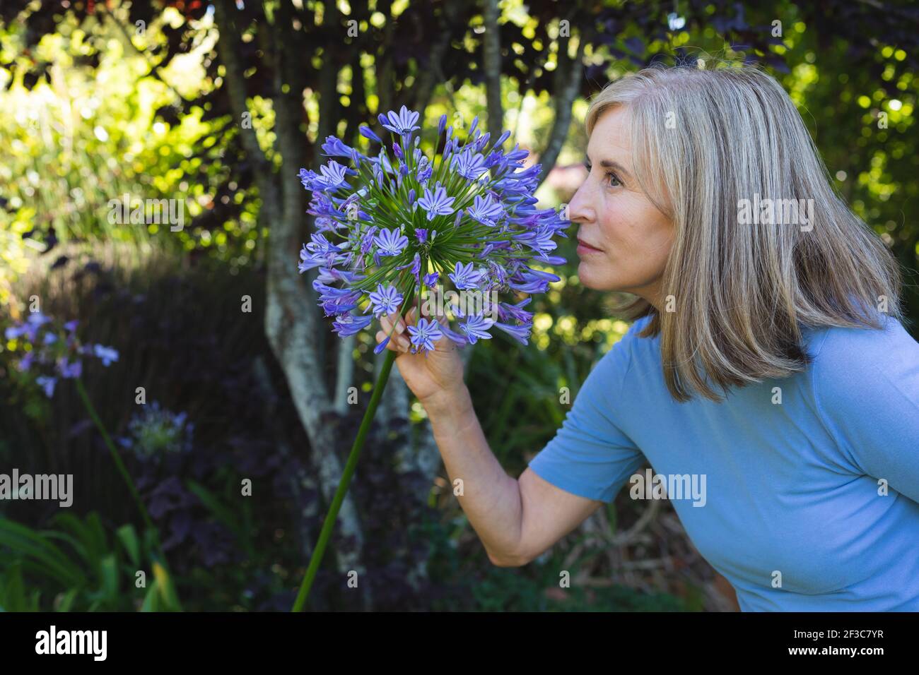 Portrait d'une femme de race blanche dans un jardin qui sent des fleurs Banque D'Images