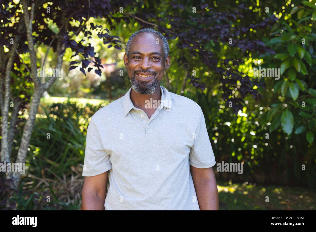 Portrait de l'homme senior de course mixte dans le jardin regardant appareil photo et sourire Banque D'Images