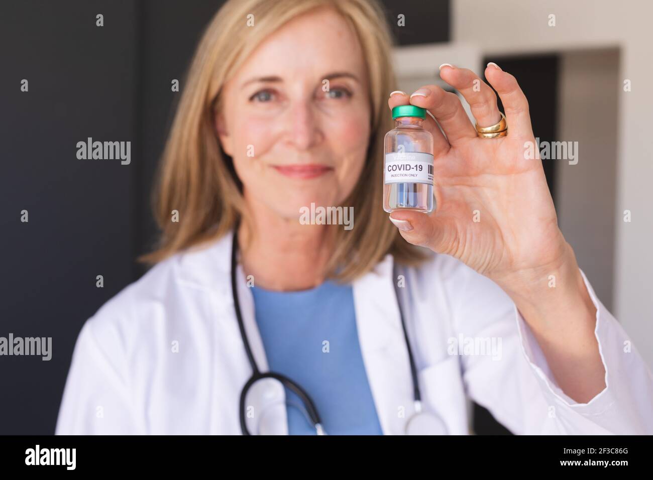 Une femme de race blanche est médecin senior et porte le vaccin Covid-19 et sourit Banque D'Images