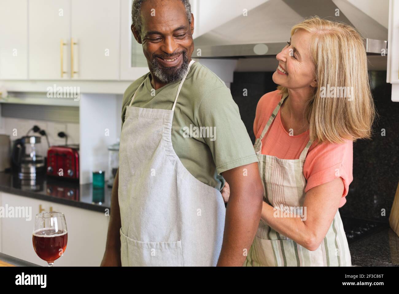 Divers couples âgés mettant des tabliers dans la cuisine avant de cuisiner Banque D'Images
