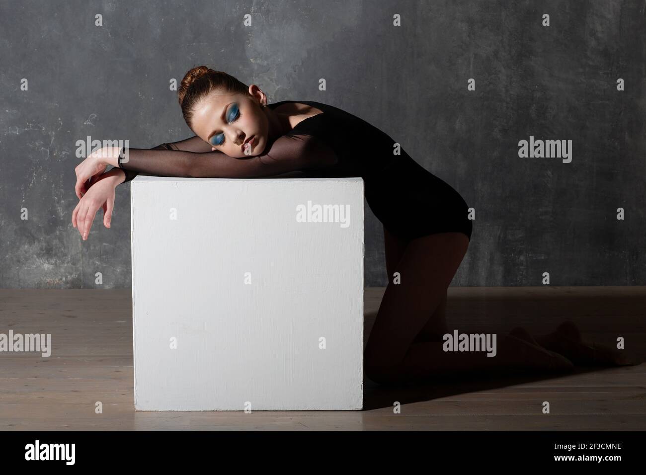 Jeune femme gymnaste professionnelle se reposant sur un cube blanc après l'entraînement. Concept de gymnastique rythmique Banque D'Images