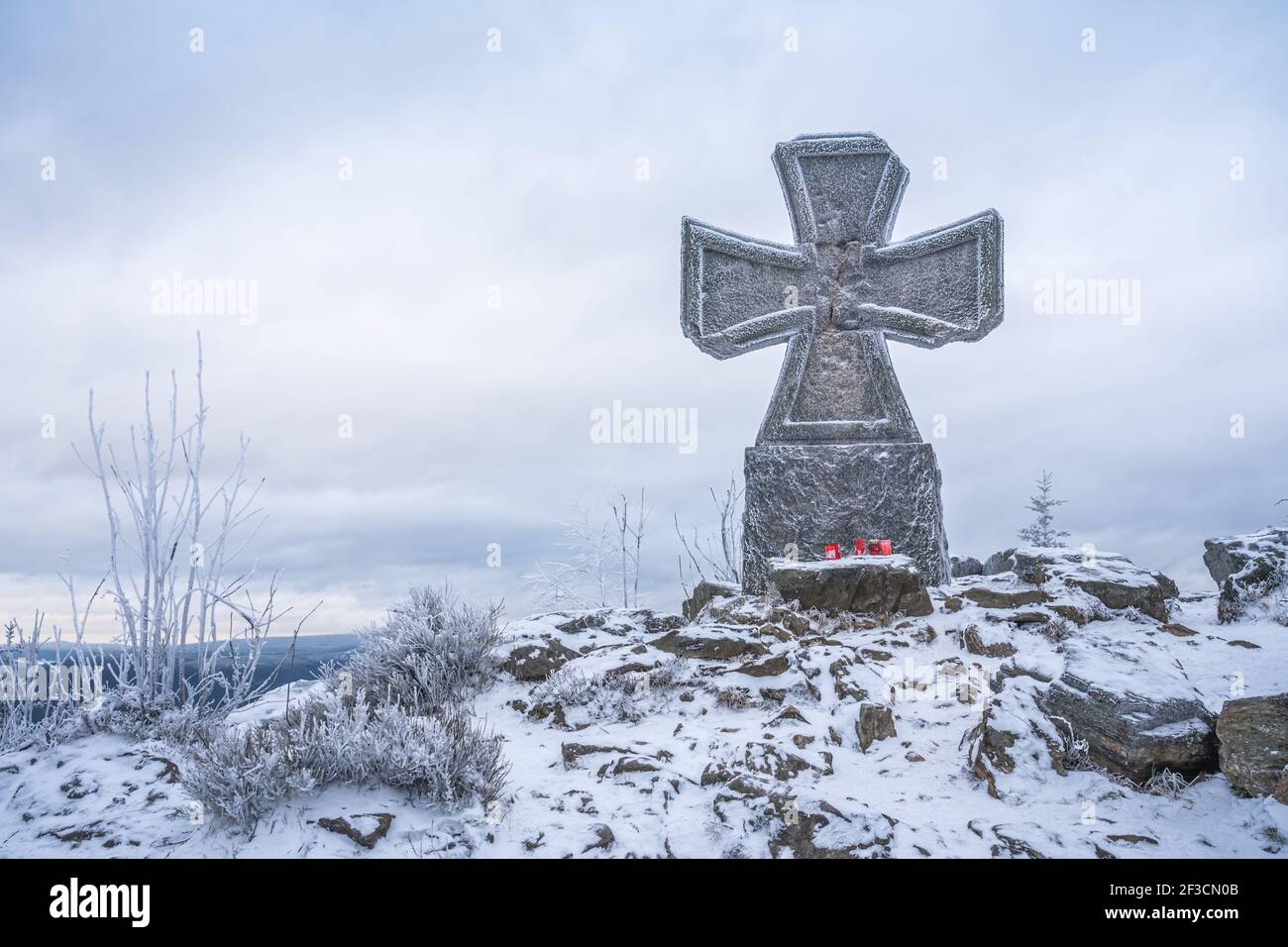 Croix de guerre en pierre près de la tour de belvédère Stepanka, à la frontière des monts Krkonose et Jizera. Jour couvert d'hiver, ciel avec nuages, arbres couverts Banque D'Images