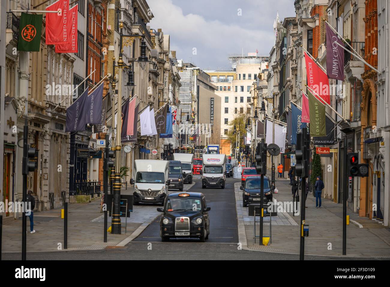 Londres, Royaume-Uni. 16 mars 2021. La circulation s'écoule sur New Bond Street, dans le centre de Londres, sans congestion durant le confinement de la pandémie Covid-19 en mars 2021 et les drapeaux des détaillants de luxe donnent une impression de normalité. Cependant, tous les magasins et galeries de luxe restent fermés et peu de piétons sont à proximité. Le grand magasin Debenhams d'Oxford Street, au centre de la tournée, est maintenant fermé définitivement. Crédit : Malcolm Park/Alay Live News. Banque D'Images