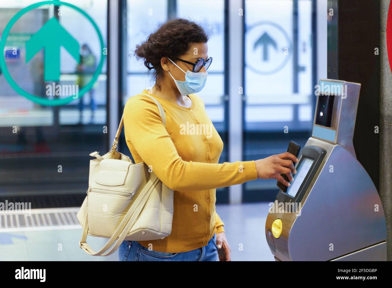 Femme payant le billet de transport à l'aide d'un smartphone et d'une machine sans contact Banque D'Images