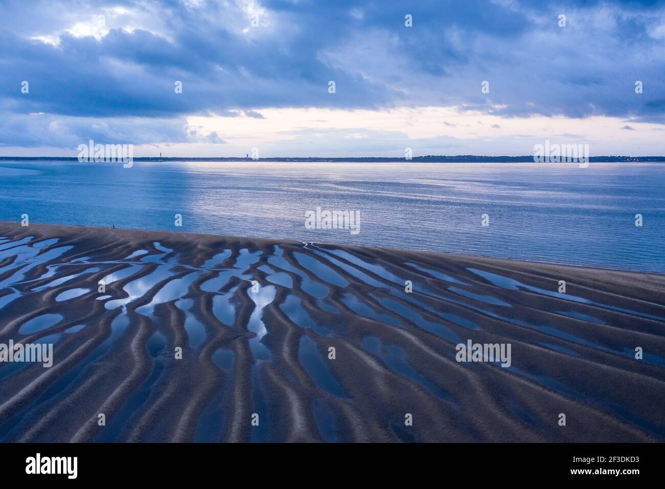 Vue en grand angle du paysage maritime à marée basse. Formes géométriques des bassins d'eau entre les vagues de sable. Banque D'Images