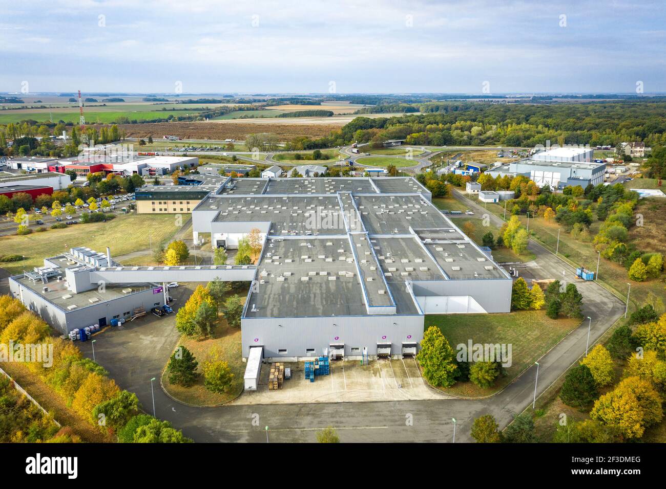 Vue de drone sur la salle de production du parc industriel d'Ablis, France. Grand bâtiment moderne avec toit plat. Industrie, transport et logistique. Banque D'Images
