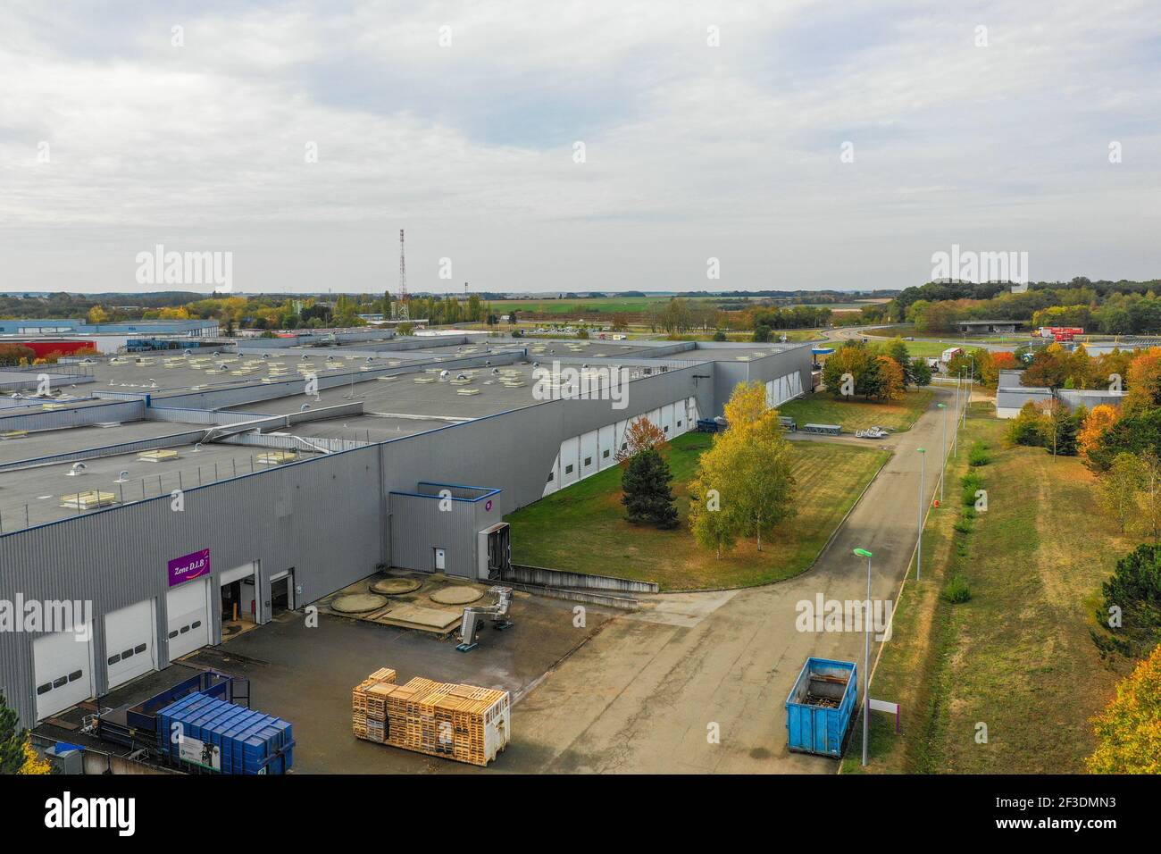 Vue en grand angle de la route menant le long d'un hall industriel plat dans une zone de production ou logistique moderne. Industrie, transport et logistique. Banque D'Images