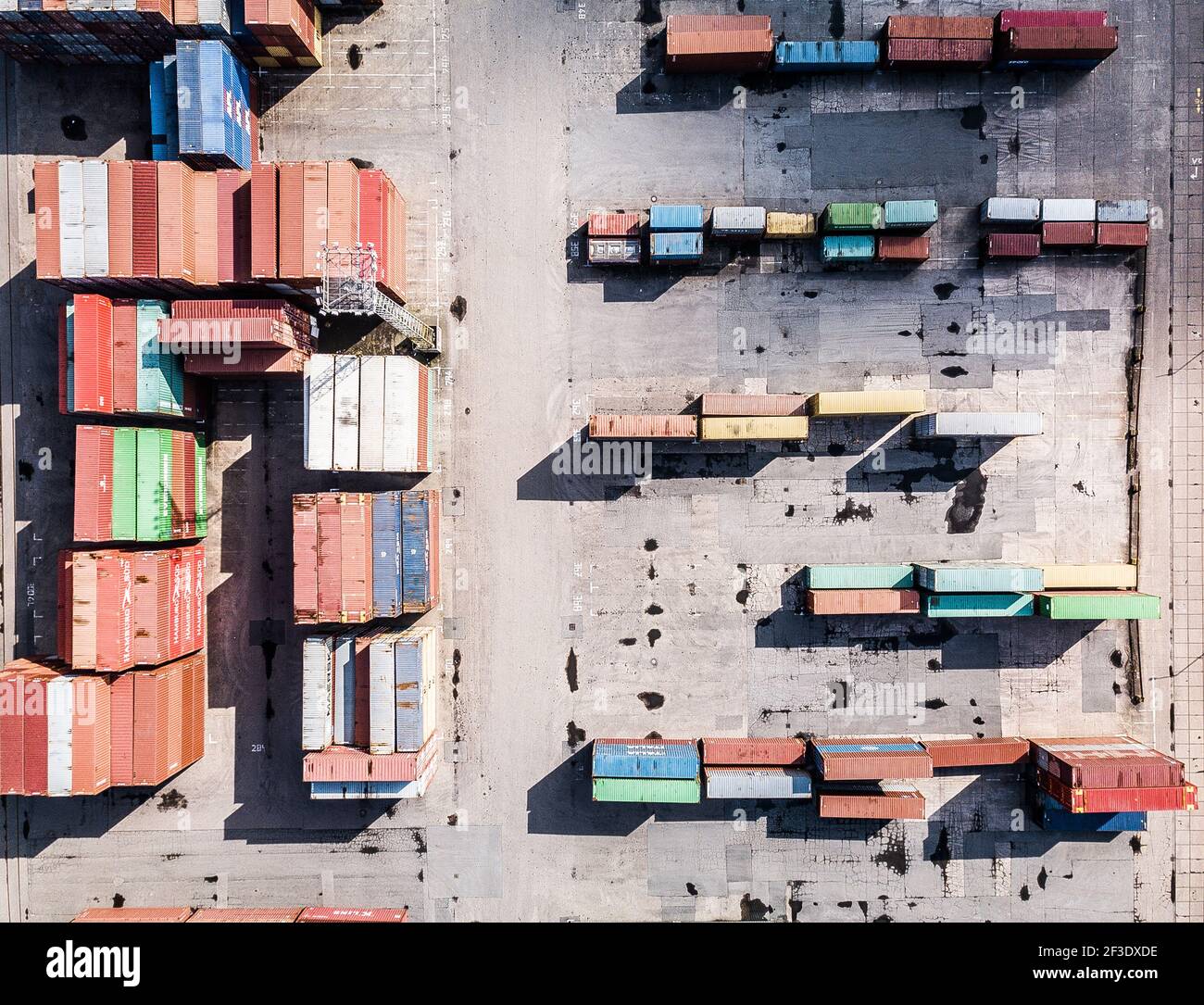 Vue de dessus vers le bas depuis le drone des conteneurs de transport empilés. Utilisation du système de transport intermodal dans les quais. Banque D'Images