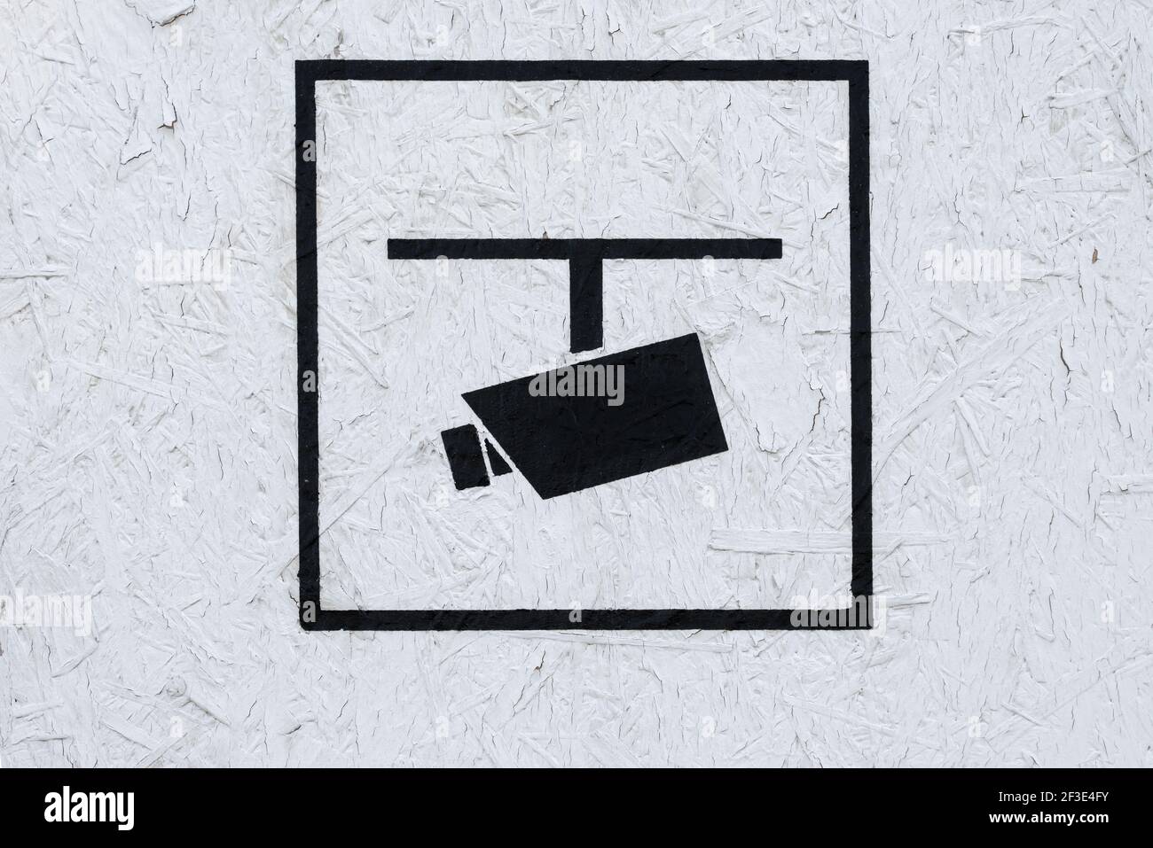 Icône noire d'une caméra de surveillance sur un bois blanc mur Banque D'Images