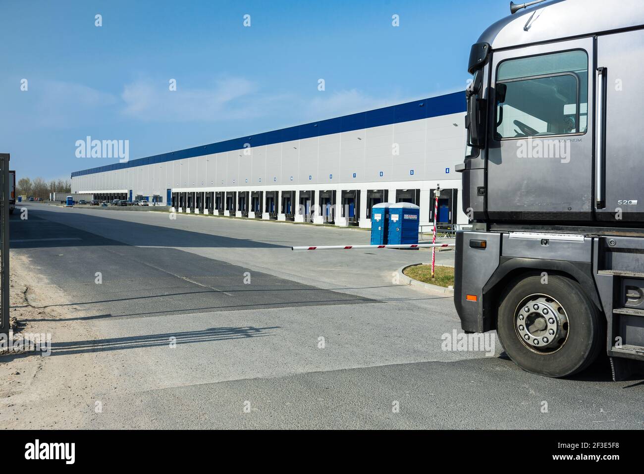 Vue rognée du chariot entrant dans le parc logistique. Cabine du chariot debout devant la barrière. Rangée de quais dans le mur du hall. Concept de transport et de logistique. Banque D'Images