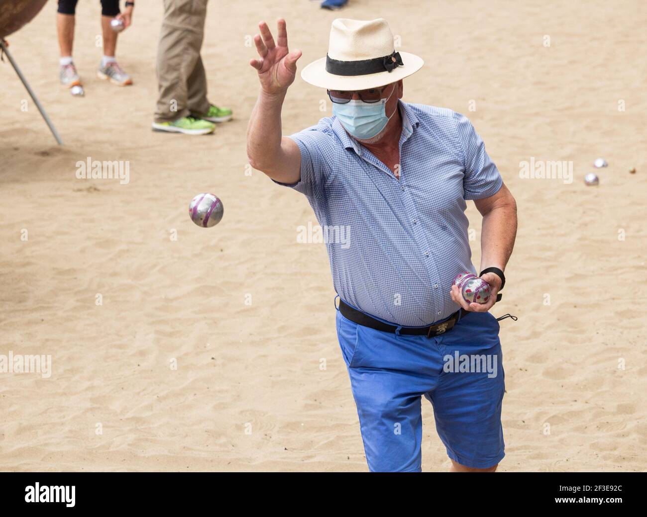 Homme portant un masque facial, couvrant jouer à Boules pendant la pandémie de Covid sur la plage en Espagne Banque D'Images