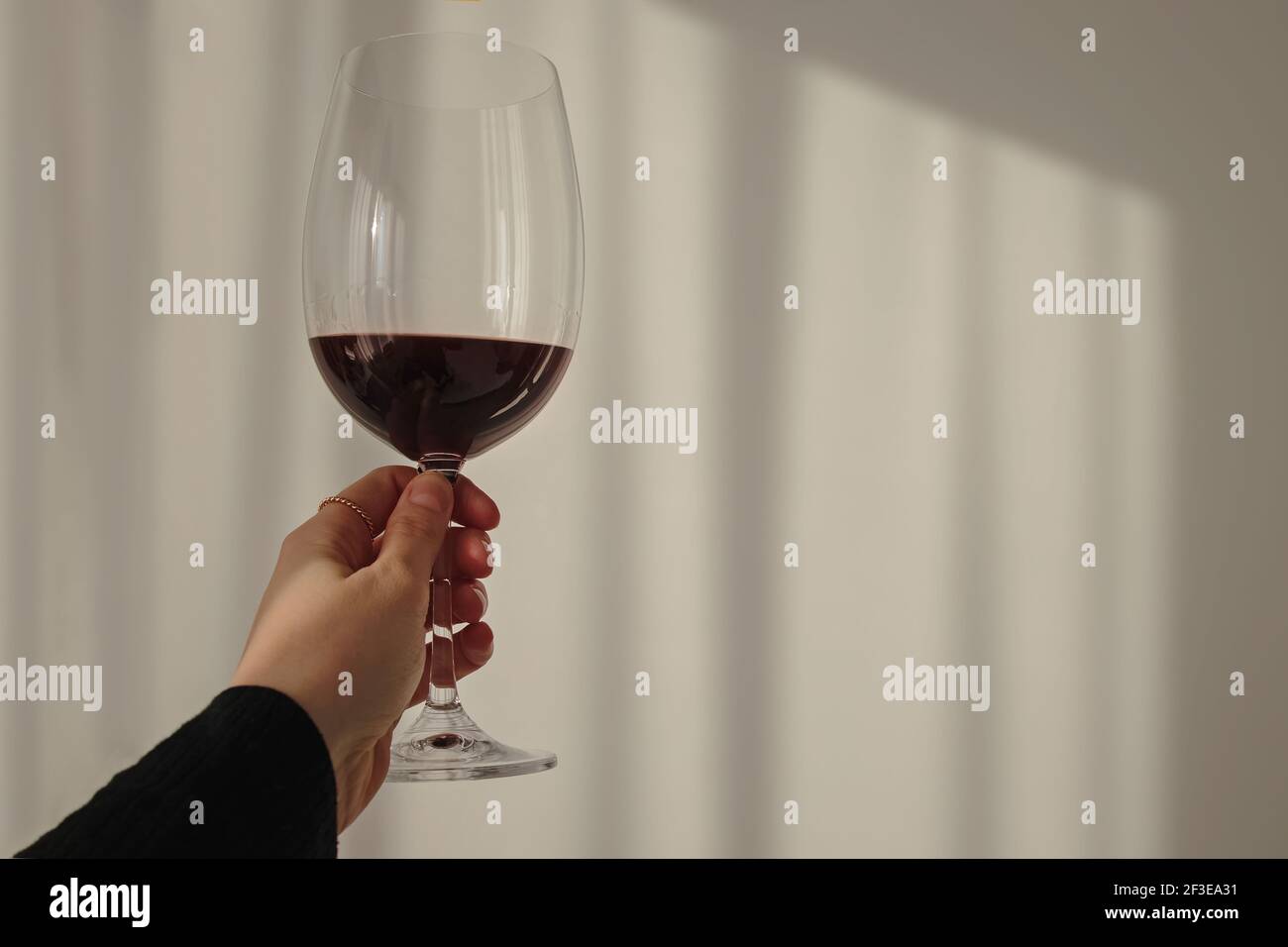 Main de femme tenant un verre avec du vin rouge Banque D'Images