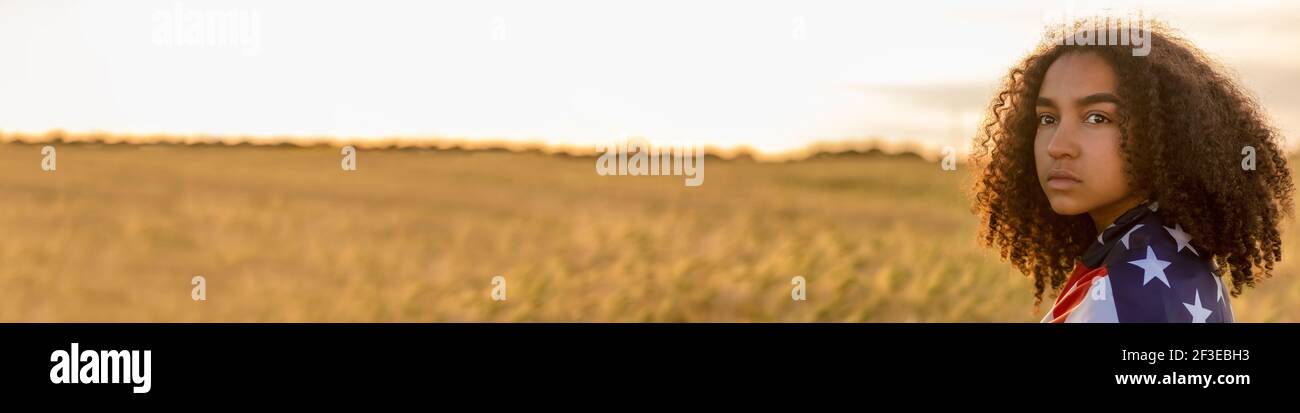 Panorama triste déprimé mixte race afro-américaine fille adolescente femme jeune femme dans un champ de blé ou d'orge Enveloppé d'étoiles et de bandes aux États-Unis Banque D'Images