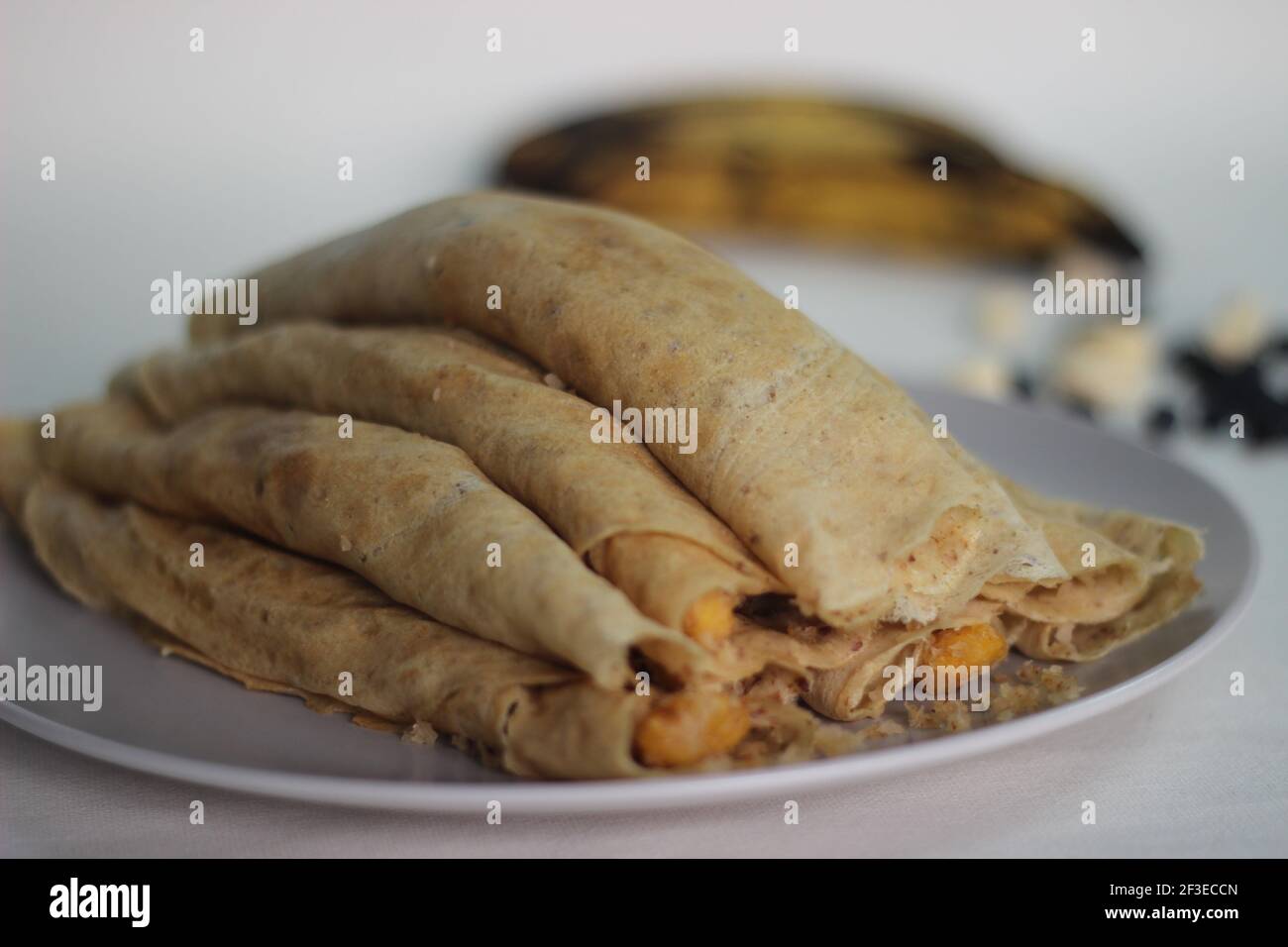 Crêpes ou crêpes plantain faites maison avec mélange de raisins de coco plantain au milieu. Prise de vue sur fond blanc. Banque D'Images