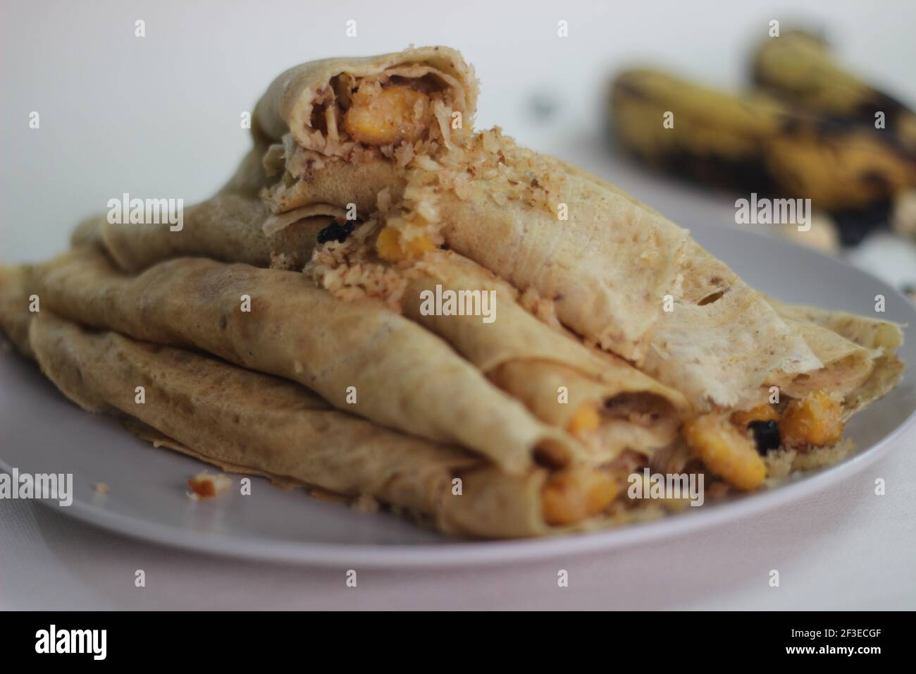 Crêpes ou crêpes plantain faites maison avec mélange de raisins de coco plantain au milieu. Prise de vue sur fond blanc. Banque D'Images