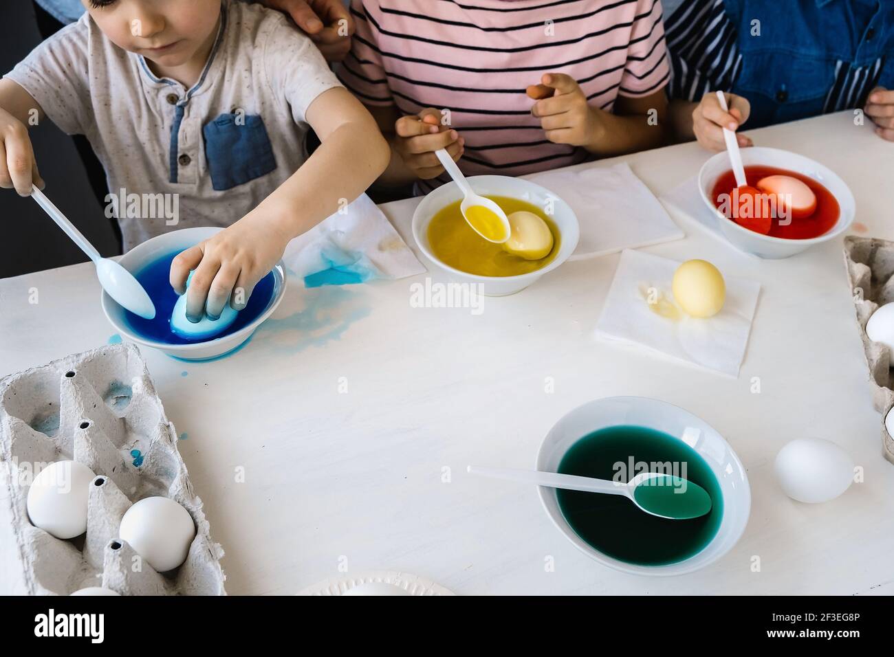 Concept de préparation. Les enfants en gros plan trempent les œufs dans un colorant liquide. Coloriage des œufs de Pâques et concept d'activité familiale Banque D'Images