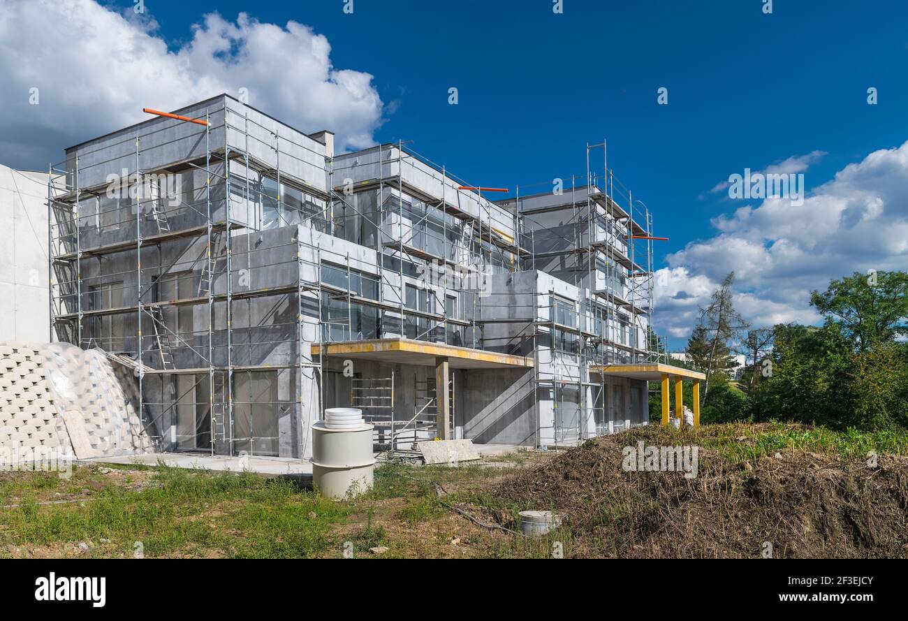 Nouvel extérieur de maison résidentielle en construction. Chantier. Ciel bleu d'été. Appartements modernes avec façade non finie et échafaudage en métal. Banque D'Images