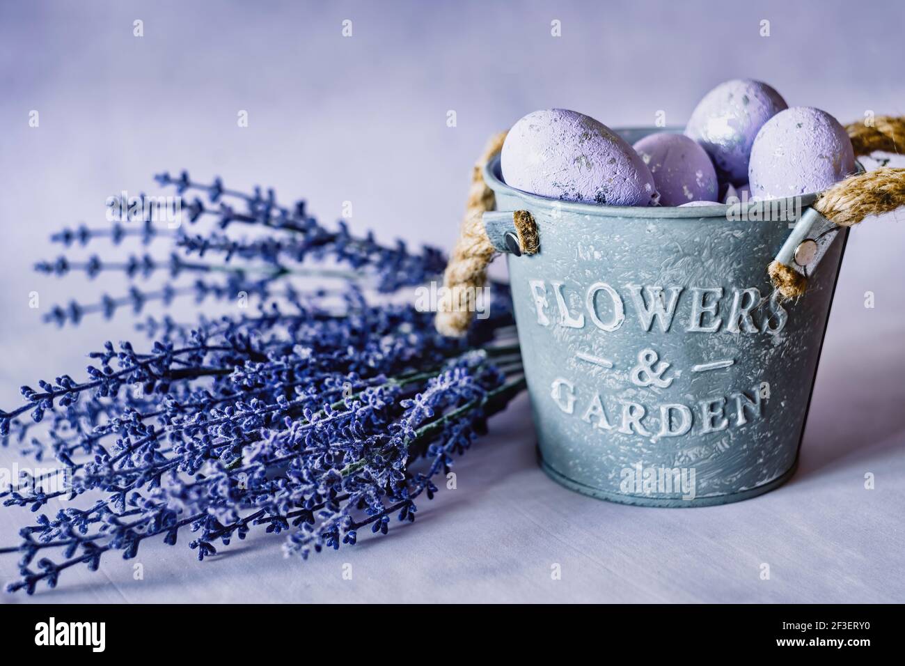 Oeufs de Pâques violets dans un pot de fer avec fleurs de lavande bleues Banque D'Images