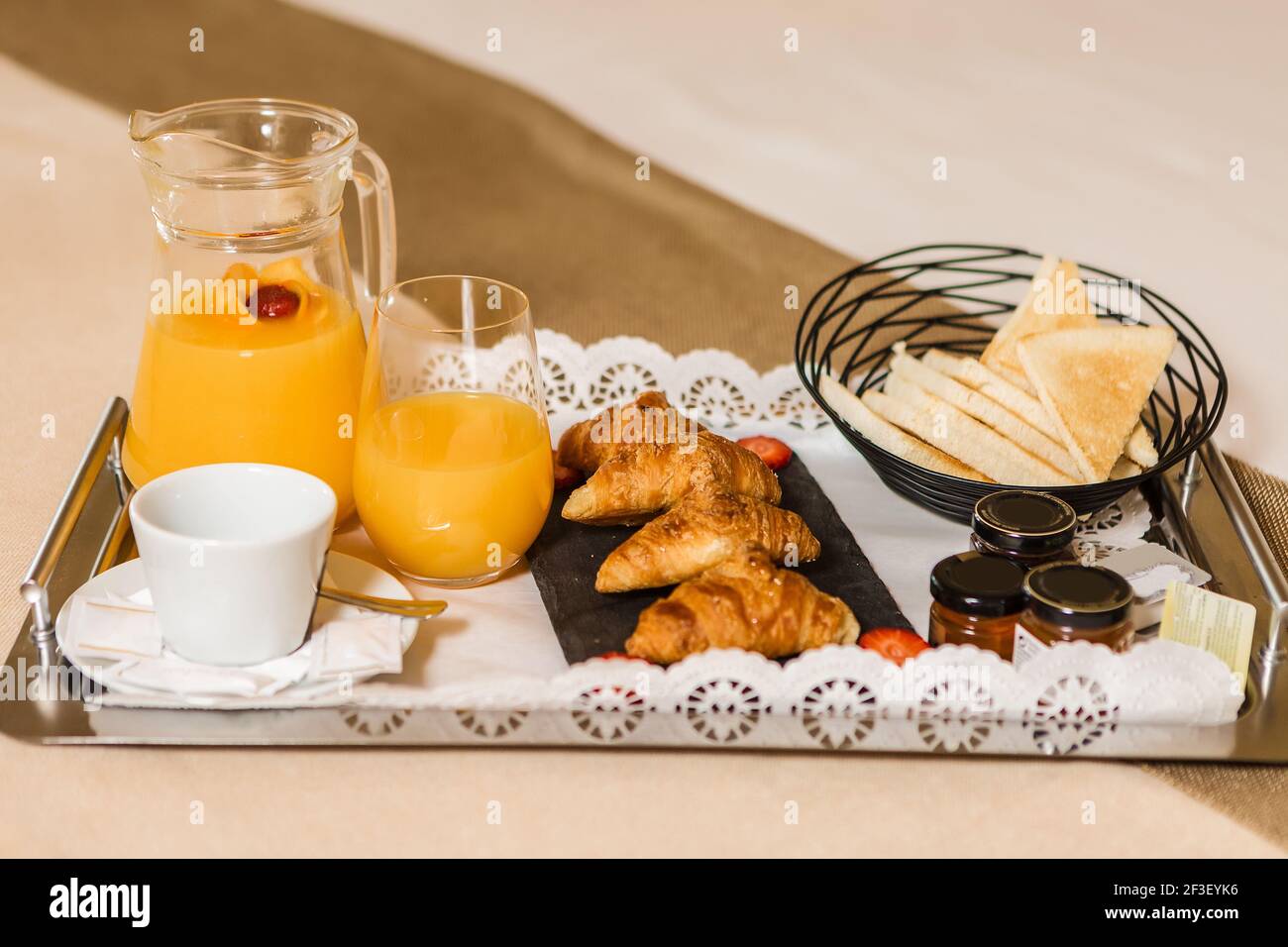 Plateau en métal avec une délicieuse pâtisserie pour le petit déjeuner et  du jus d'orange frais placé sur le lit dans la chambre d'hôtel Photo Stock  - Alamy