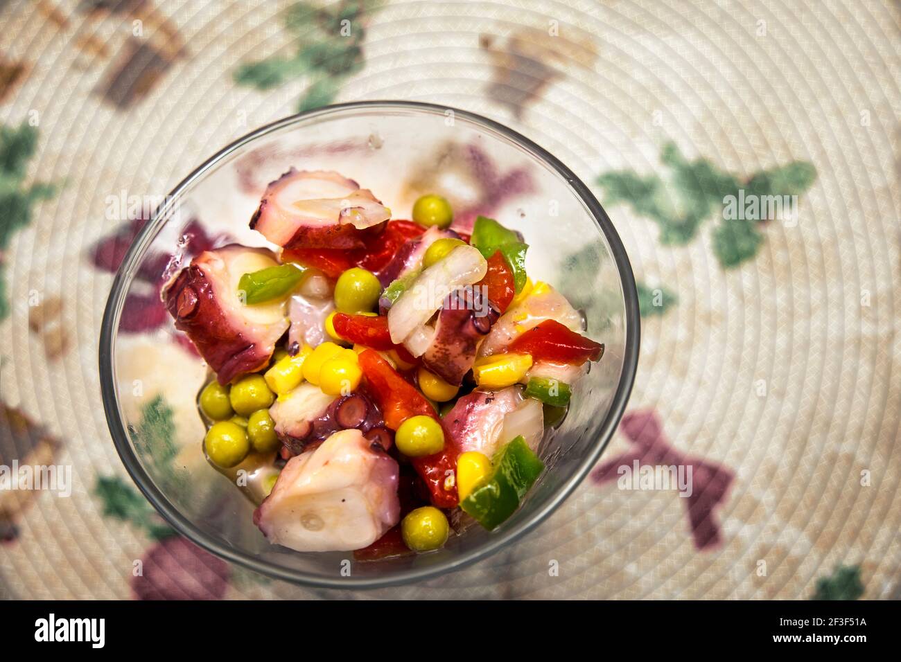 bol en verre avec salade multicolore de poulpes, petits pois et poivrons Banque D'Images